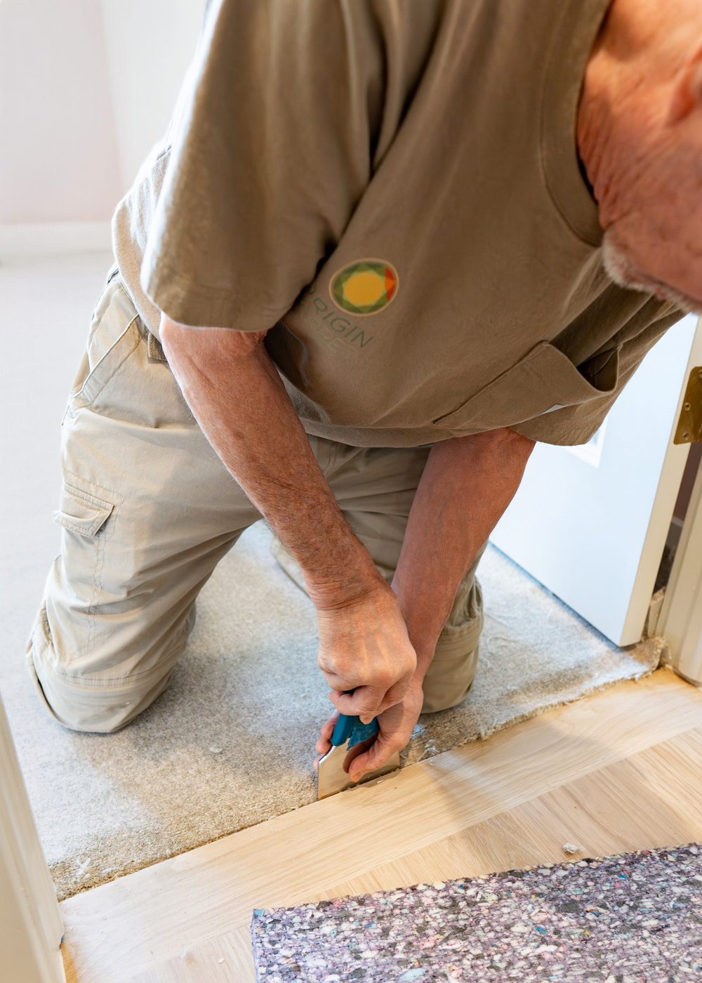 Origin Carpet installer trimming carpet at a hardwood transition during a Treasure Valley installation